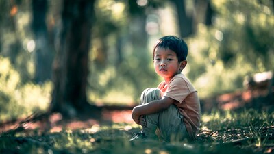 Asian boy sitting in forest