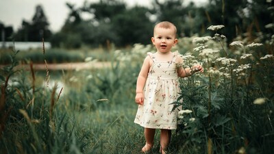 Baby girl touching wildflowers in field