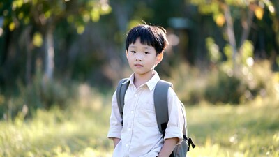 Asian boy with backpack in grass