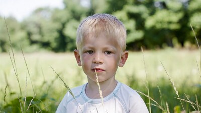 Blond boy holding grass in field