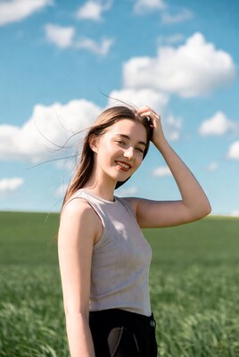 Smiling woman touching hair in green field