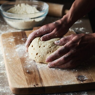 Hands kneading dough on wooden board