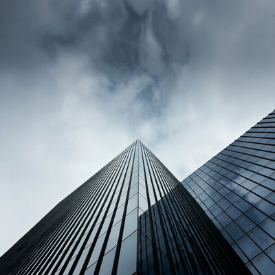 Tall glass skyscraper under cloudy sky
