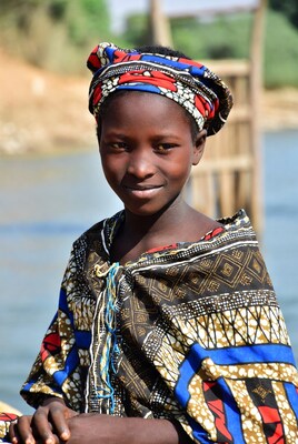 African girl in colorful headwrap by river