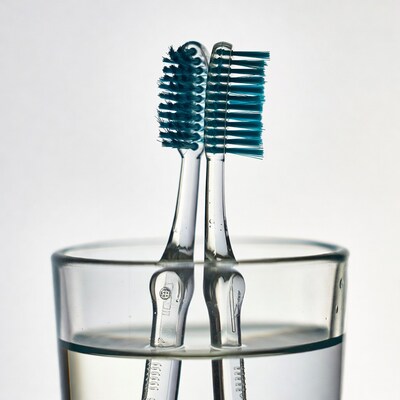 Two blue toothbrushes in glass
