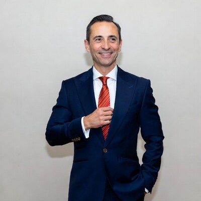 Man adjusting red tie in navy suit