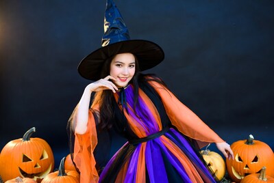 Asian woman in witch costume with pumpkins