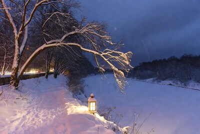 Lantern glowing on snowy riverbank