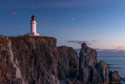 White Lighthouse on Cliff at Twilight with Moon