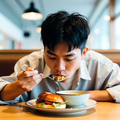 Asian man eating soup with burger