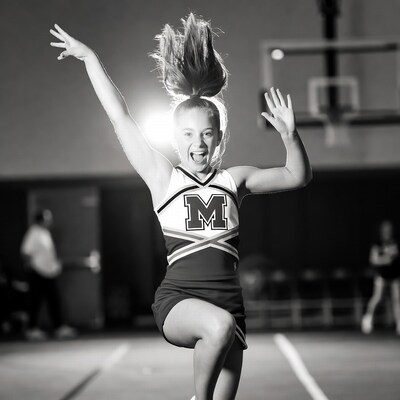 Cheerleader girl jumping with arms raised