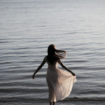Woman in dress facing lake