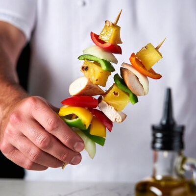 Man holding chicken vegetable skewers