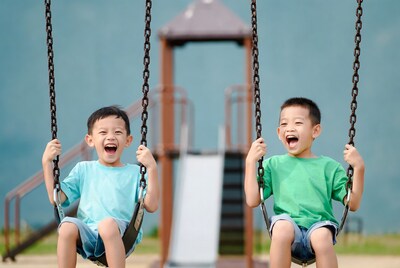 Asian boys laughing on swings