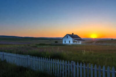 White farmhouse at sunset with picket fence