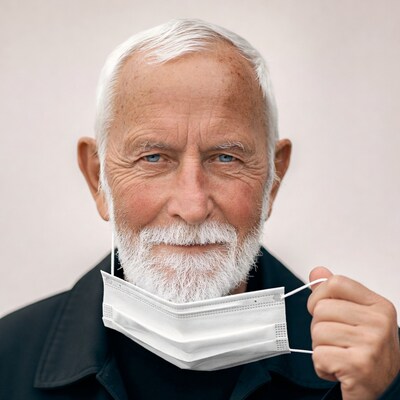 Elderly man holding white face mask