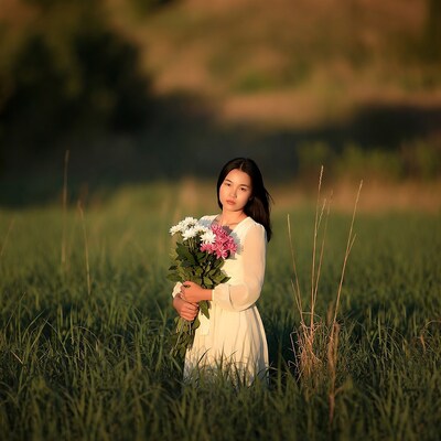 Asian girl holding flowers in grass