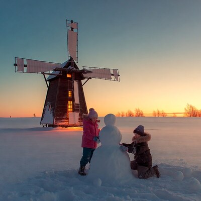 Children building snowman near windmill