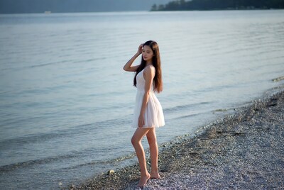 Asian woman in white dress at lakeshore