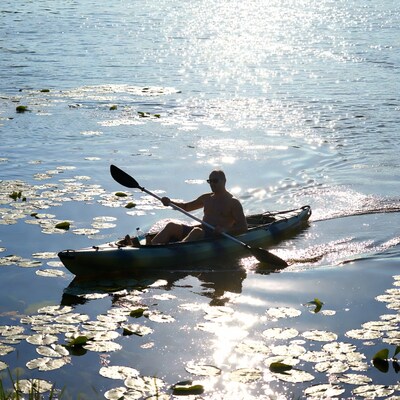 Man kayaking among water lilies