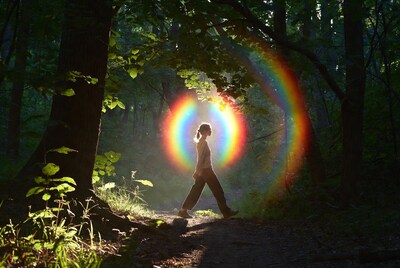 Woman walking through rainbow forest path