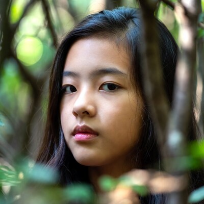 Asian girl peeking through bushes