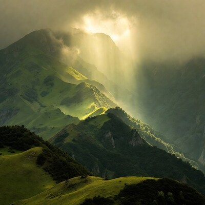 Sunbeams over green misty mountains