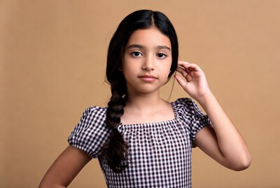 Girl touching ear in checkered dress
