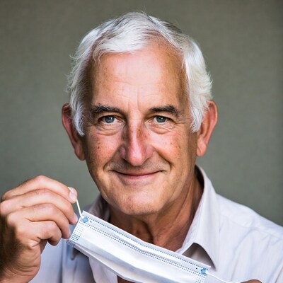 Elderly man holding white face mask