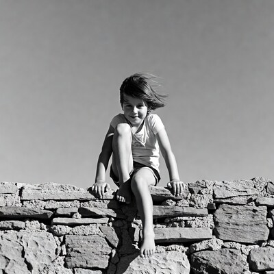 Girl sitting barefoot on stone wall