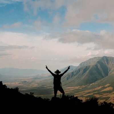 Man raising arms on mountain peak