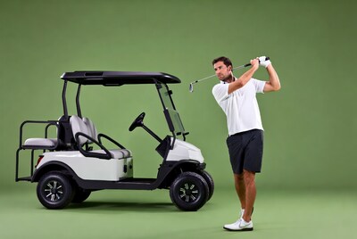 Man swinging golf club by cart