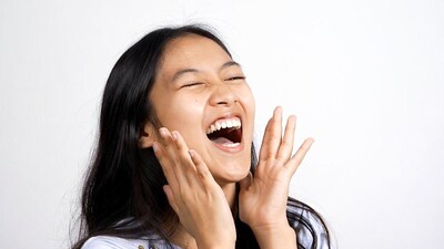 Asian woman laughing with hands raised