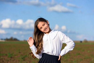 Girl waving in school uniform outdoors