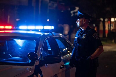 Police officer standing by patrol car at night