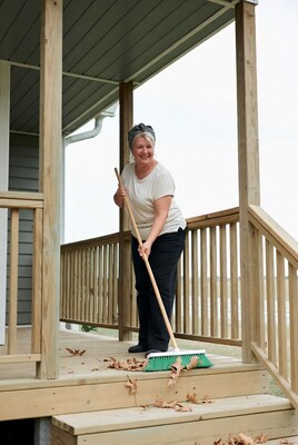 Woman sweeping leaves on porch stairs