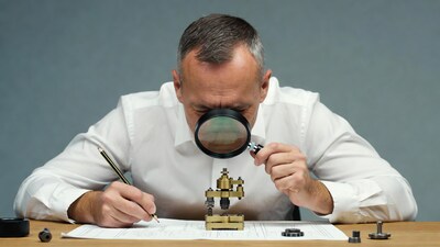Man using magnifying glass on engineering drawing