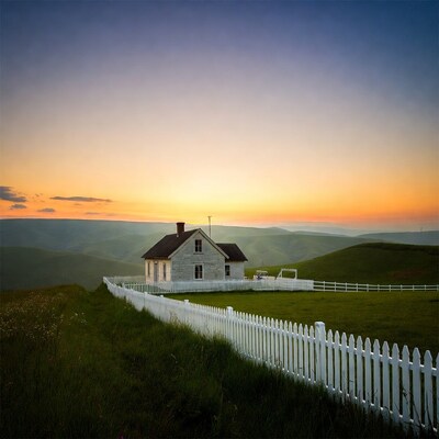 White farmhouse on hill at sunset