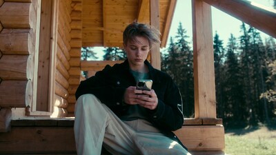 Young man using phone on cabin porch