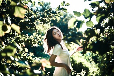 Asian woman in green foliage sunlight