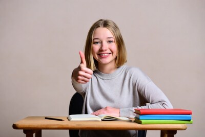 Young woman giving thumbs up at desk