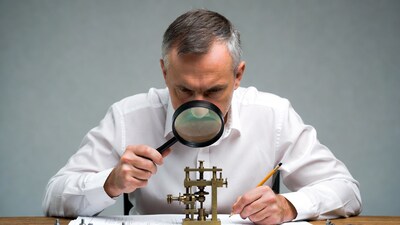 Man examining brass mechanism with magnifying glass