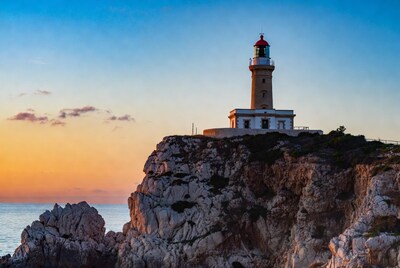 Lighthouse on cliff at sunset