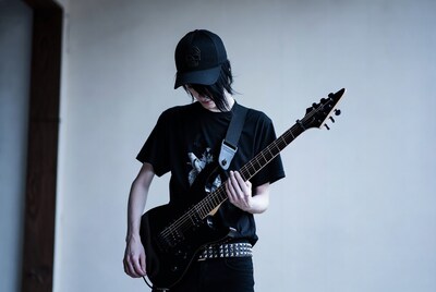 Young man playing black electric guitar