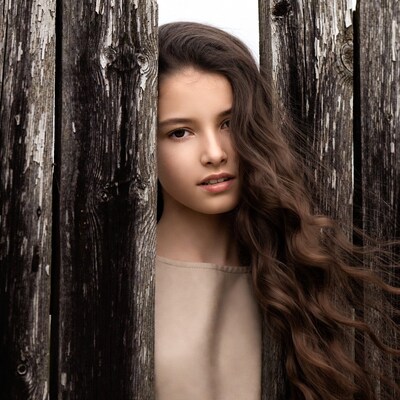 Girl peeking through wooden fence