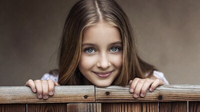 Girl peeking over wooden fence