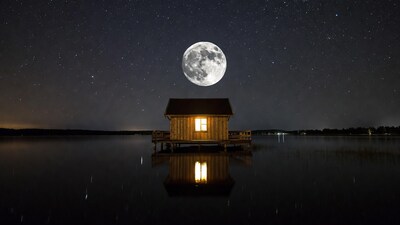 Wooden cabin on lake under full moon