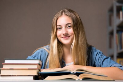 Teen girl reading books at library table