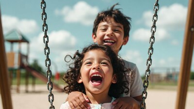 Boy and girl laughing on playground swing