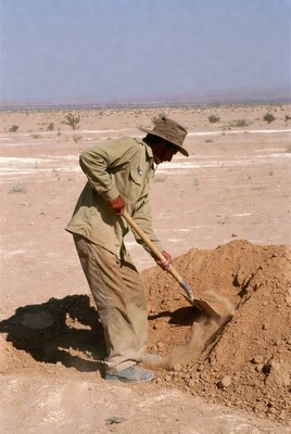 Man shoveling sand in desert
